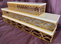 Three gold-tone and white metal accent shelves stacked to show sizes and geometric sides