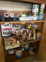 Full view of three shelves showing paint cans, sealer, caulk, accessories