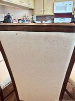 close view of chair back showing cream linen upholstery and dark wood frame