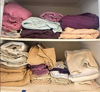 Two shelves filled with folded sheet sets in various colours and fabrics