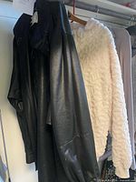 Black faux leather jacket and cream fleece jacket hanging