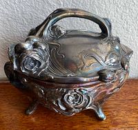 Overall view showing floral relief, handle, feet, and broken hinge area