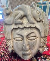 Front view of carved stone mask with animal figure on headdress