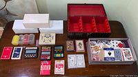 All items laid out on table showing card decks, handheld poker games, chip tubes, white boxes and open 8-track case