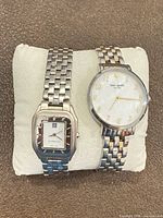 Two women’s watches on display cushion: Givenchy rectangular and Kate Spade round