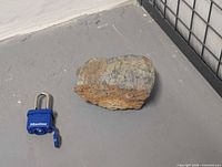 Full view of galena specimen next to padlock for scale