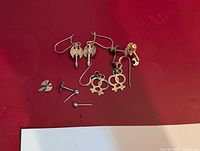 All five pairs of sterling silver earrings laid out on red surface