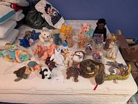 Full view of assorted Beanie Babies on mattress with bin