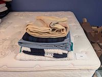 Stack of five blankets on mattress showing overall lot