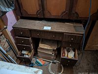 Full desk showing open drawers, cardboard boxes of tile beneath, miscellaneous items