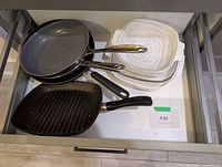 Drawer view showing three frying pans, grill pan, and two CorningWare casseroles with lids