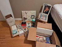 Overview of lot showing boxes with magazines, memo board, doll box, sandals package, wine-stain kit, ornament, coins not visible