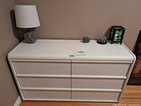 Front view of dresser with lamp and ornaments