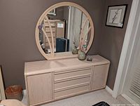 Front view dresser with attached round mirror, two ceramic vases on top