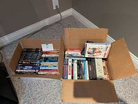 Two open cardboard boxes filled with assorted DVD movies; shows overall quantity and variety.