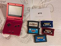 Open red Game Boy Advance SP with five cartridges displayed