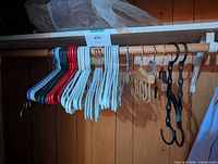 Full view of assorted plastic, metal, wood hangers on rod
