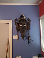 Front view of carved wooden mask with feather headdress and tassels