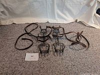 Complete set of four crampons and two leather straps laid out on carpet