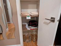 Closet view showing shelves with linens and five glass vases on floor