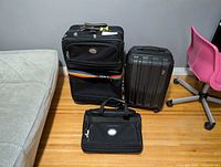 Three luggage pieces: Heys hardshell carry-on, American Tourister upright, American Tourister carry bag
