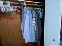 Row of shirts, blazer, jacket hanging on closet rod