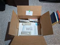 Open box showing Wii retail box, silicone jackets, and rows of Wii game cases