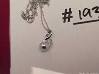 Pearl pendant necklace showing sterling silver swirl setting, round white pearl, fine chain and lobster clasp