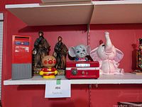 All items on shelf: mailbox bank, samurai pairs, Anpanman bank, red vault safe, grey elephant bank, pink elephant bank