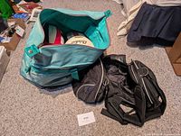Teal duffel bag open, volleyballs visible, black duffel beside