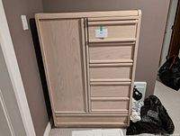Front view of light wood standing dresser with cabinet door and five drawers