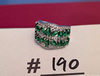 Front view of sterling silver ring showing three rows of green stones and clear accents