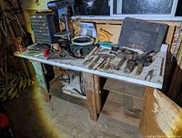 Wide view of workbench showing assortment of tools including planes, hammer heads and vise