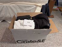 Box containing assorted folded clothes and black leather gloves