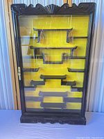 Full view of cabinet closed showing exterior finish, decorative crest, glass door and internal shelves