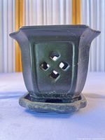 Front view showing dark green glaze, diamond cut-outs and attached saucer