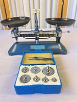 Full view of balance scale with both pans and weight set in front