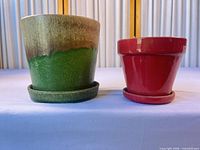 Both planters side by side on saucers showing exterior colors and size comparison