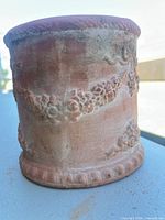 Side view showing ornate floral garland relief and weathered patina