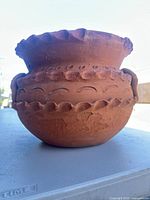 Side view of terracotta planter pot showing decorative relief and general form