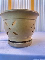 Side view of terracotta planter showing vent cut-outs, rim shape, base slot, and color
