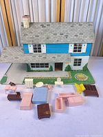 Front view of Marx tin litho dollhouse with all plastic furniture pieces laid out