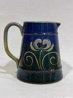 Side profile of ceramic jug displaying gradient glaze and floral motif
