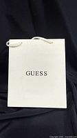 Front of cream GUESS gift box showing rope handles and exterior logo