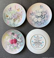Fronts of three plates and back of one plate showing floral designs, butterflies and gold rims