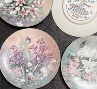 Group of four plates showing fronts with floral butterfly artwork and one back, gold rims visible