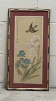 Full view of framed silk painting leaning against wall