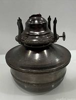 Front view of metal oil lamp base showing burner and reservoir