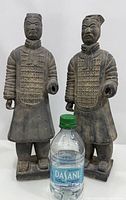 Both statues side by side with water bottle for scale