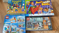 Four boxed items laid out: two board games, two LEGO sets